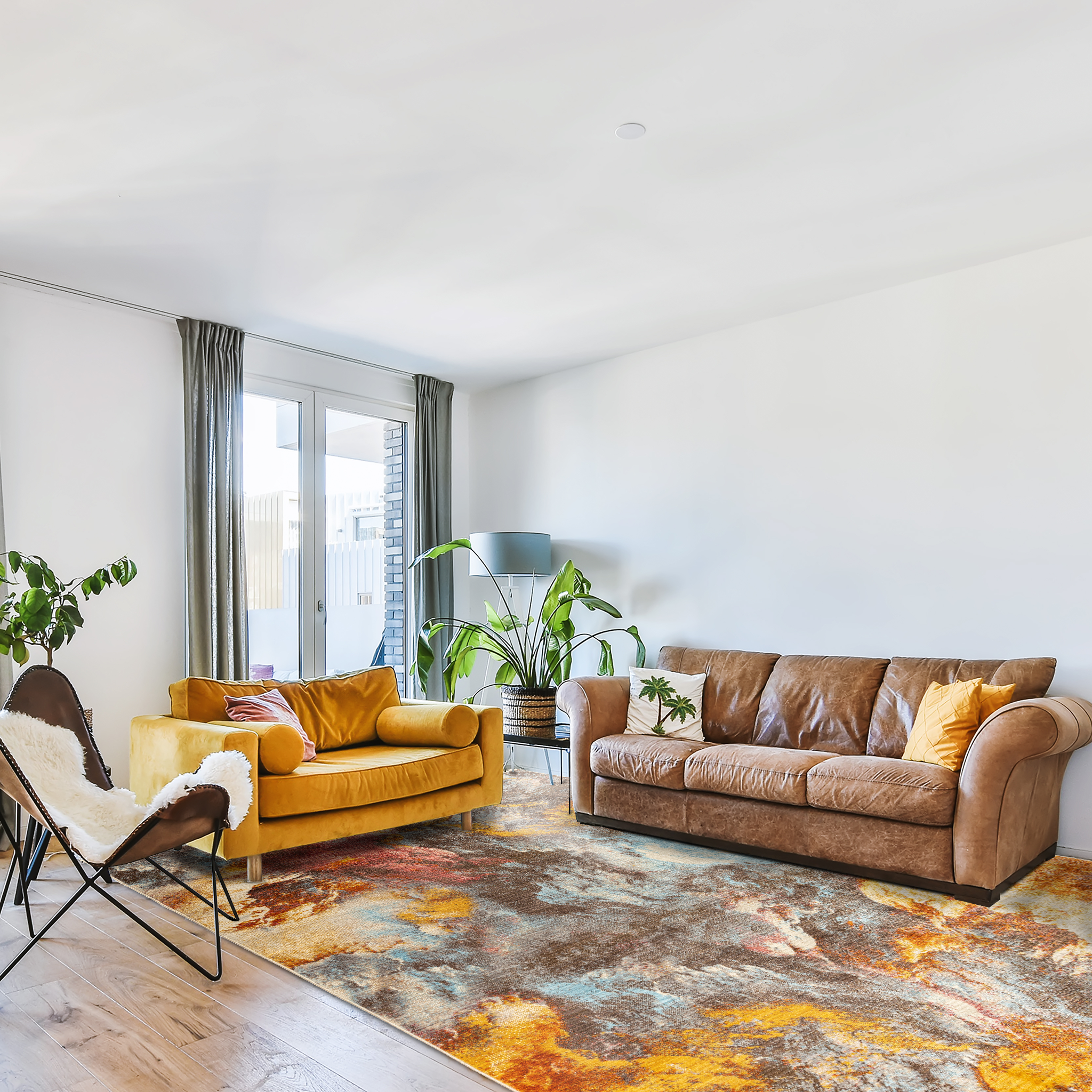 Bright living room with brown and beige sofas and chair, large plants and Mystic Art Rug in vibrant brown, blue, mustard yellow hues 